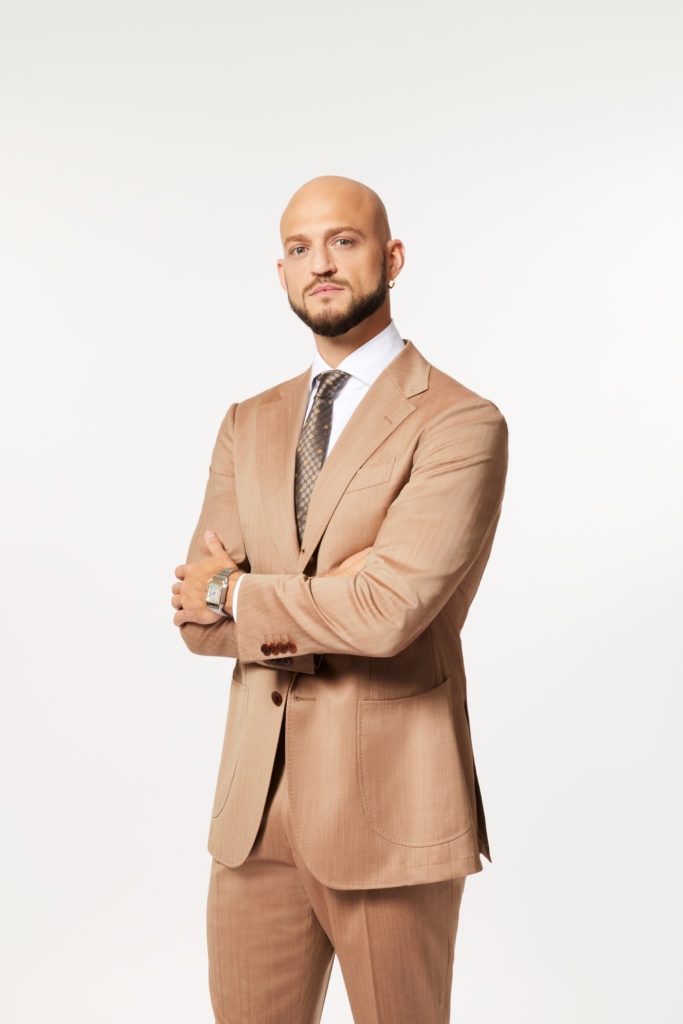 Nile Lundgren crosses arms over tummy while wearing beige suit on Owning Manhattan.