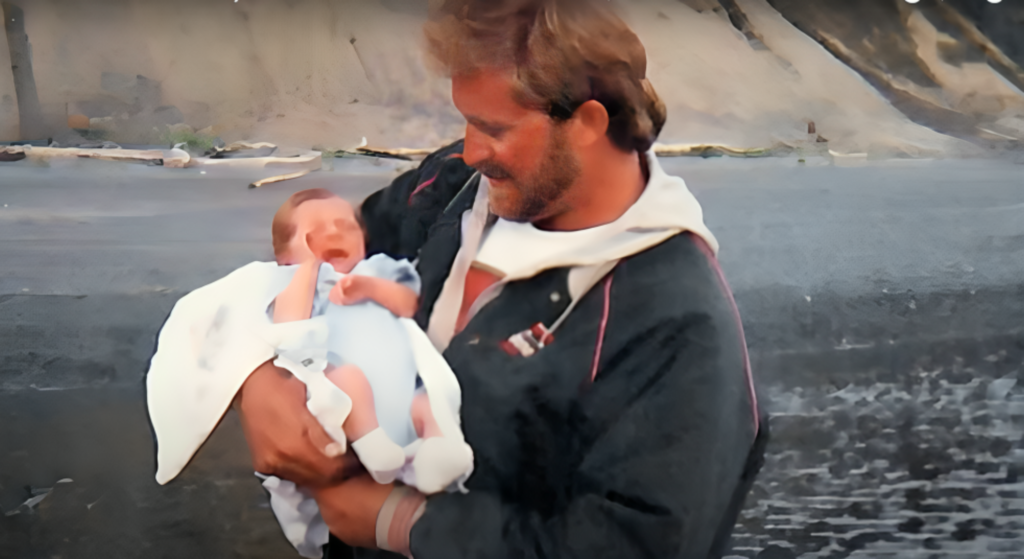 An old photograph of Jack's dad holding Jack as a baby dressed in blue in his arms.