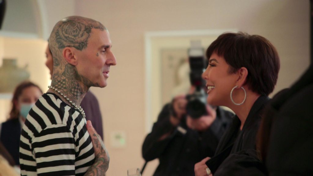 Travis Barker holds chest while smiling at Kris Jenner, who smiles back on The Kardashians.