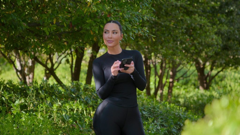 Kim Kardashian looks to left while on phone surrounded by trees on The Kardashians.