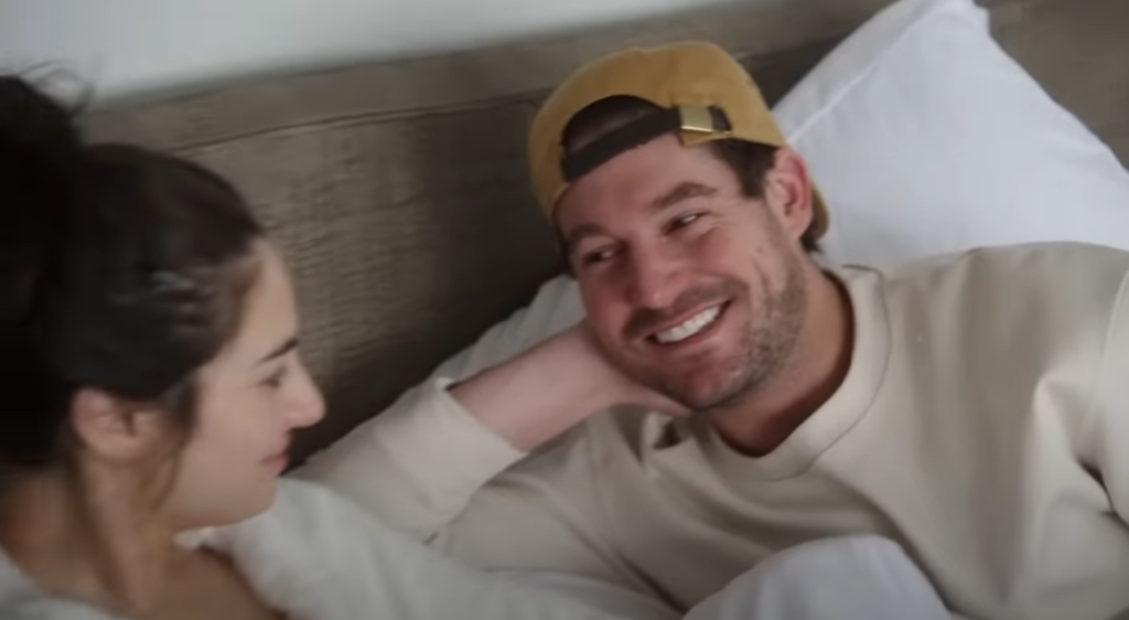 Craig Conover smiles at Paige DeSorbo as they lie in bed on Summer House.